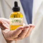 Hand of male doctor holding dropper of CBD solution