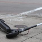 Rental scooter left abandoned on empty sidewalk laying on its side