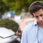 Young man holding neck after being injured in car accident