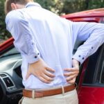 man holding back from driving back pain