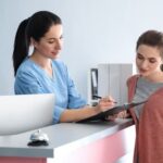 Two women in a chiropractor's office speaking at the front desk