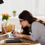 Woman slouching over laptop at her desk.