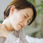 Asian woman rubbing her neck.