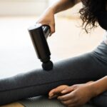 Woman using massage gun on her leg.