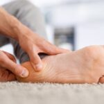 Male hands massaging the heel of a bare foot.