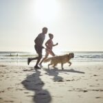 Couple exercising on Pompano beach with their dog