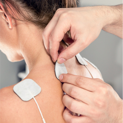 A chiropractor performing a spinal adjustment on a patient. The patient is lying face down on a treatment table while the chiropractor uses their hands to apply gentle pressure to the patient's upper back.