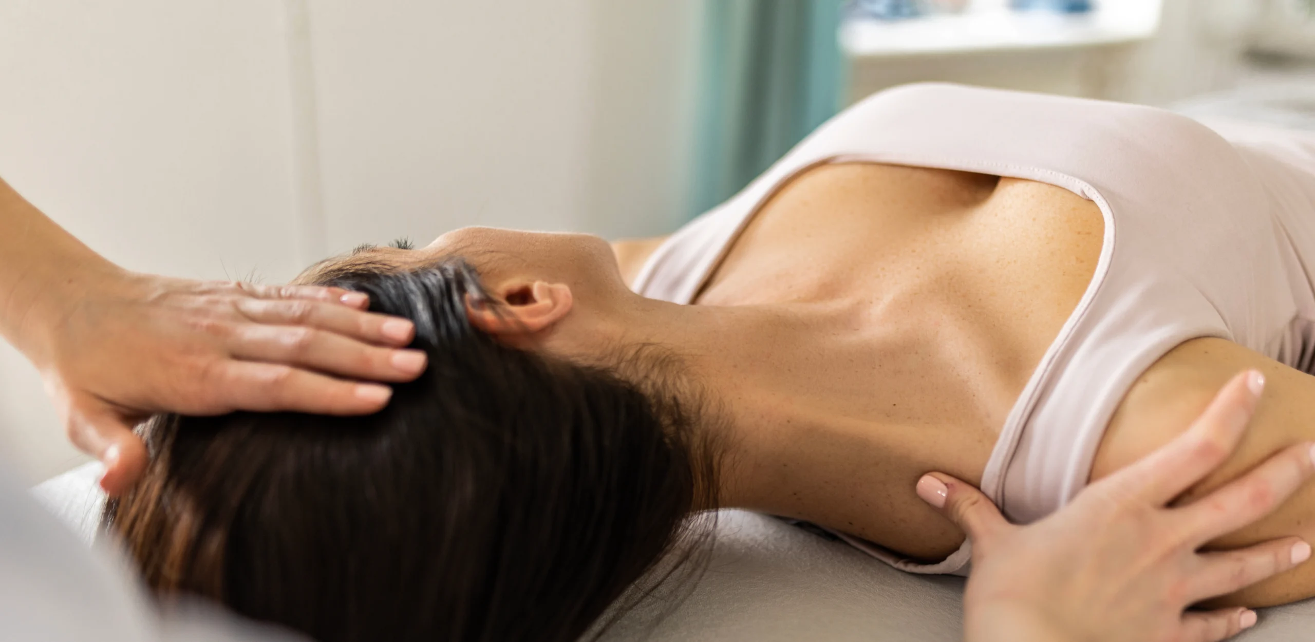 A chiropractor performing a spinal adjustment on a patient in a clinical setting. The patient, lying on a treatment table, receives focused care from the chiropractor's skilled hands, emphasizing professional healthcare in a modern environment.