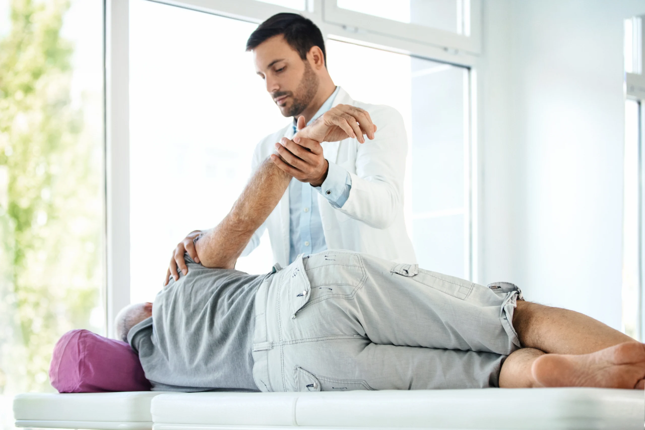 A chiropractor performing a chiropractic adjustment on a patient's neck in a clinical setting. The patient is seated and wearing a gown while the chiropractor gently manipulates the cervical spine, demonstrating specialized care in chiropractic medicine.