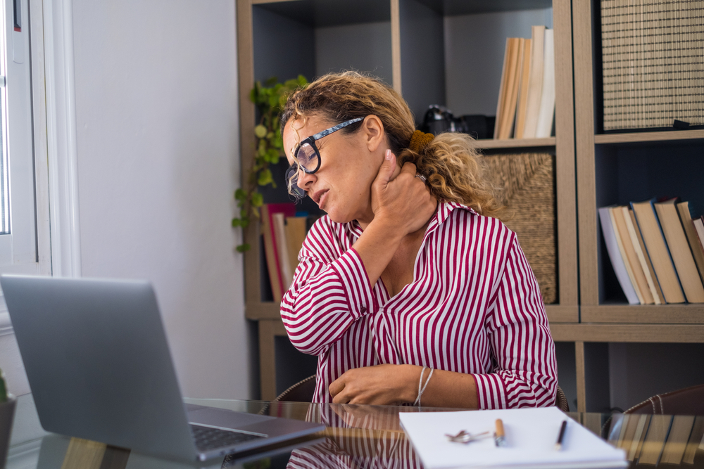 Woman at a desk holding her neck.