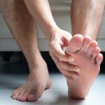 Male hands holding the sole of his foot.