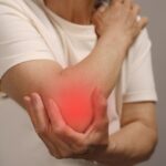 Man holding elbow with red glow to indicate pain.