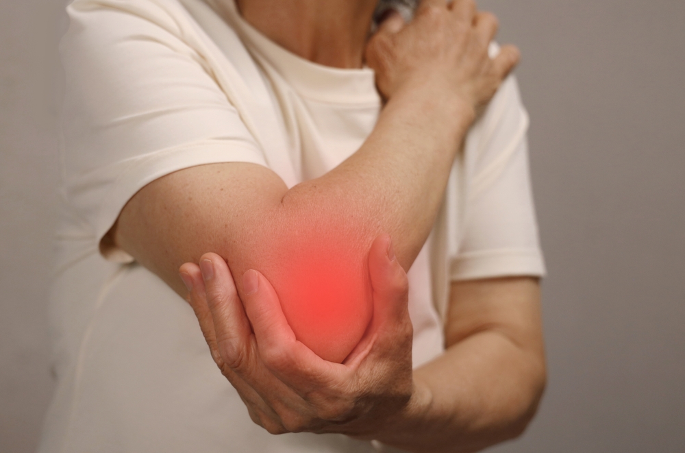 Man holding elbow with red glow to indicate pain.