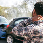 Man rubbing his neck because of whiplash pain after car accident.