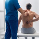 Chiropractor examining patient with spine pain.