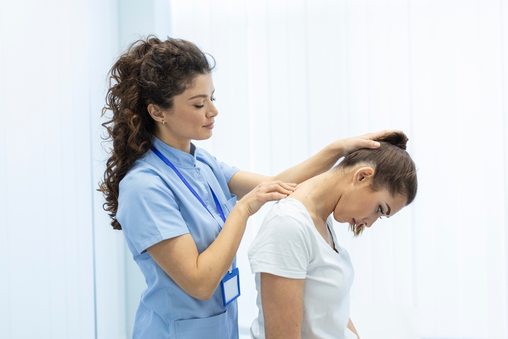 Chiropractor performing a neck and shoulder adjustment on a patient in a clinical setting.