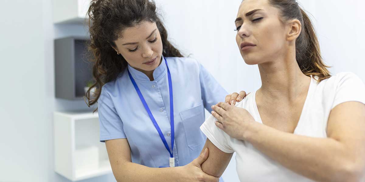 A healthcare professional evaluates a patient's injury, providing targeted shoulder pain treatment and physical therapy.
