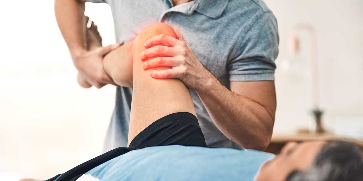 A therapist provides professional joint pain treatment in Weston, FL, gently stretching a patient’s knee with a red glow highlighting discomfort.