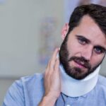 A man wearing a white cervical neck brace, illustrating how long it takes to recover from a whiplash injury.