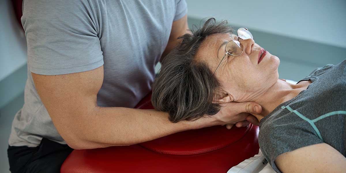 Chiropractor performing gentle neck therapy on a lying patient to help relieve persistent post-concussion neck pain and stiffness.