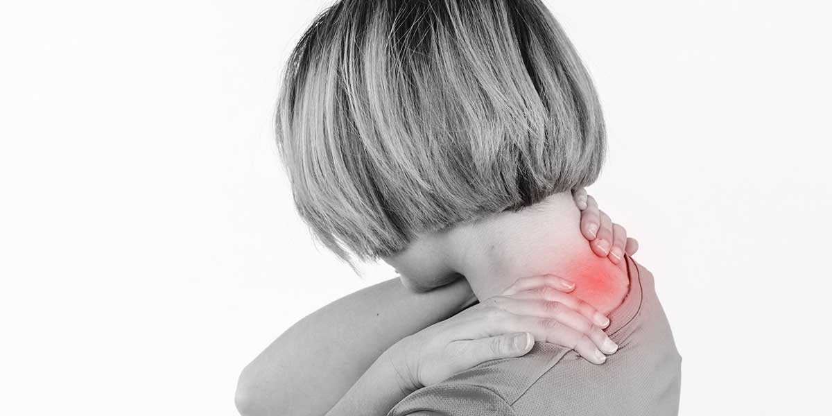 Woman clutching her painful neck, highlighting the discomfort caused by a reversal of the natural cervical spine curve.