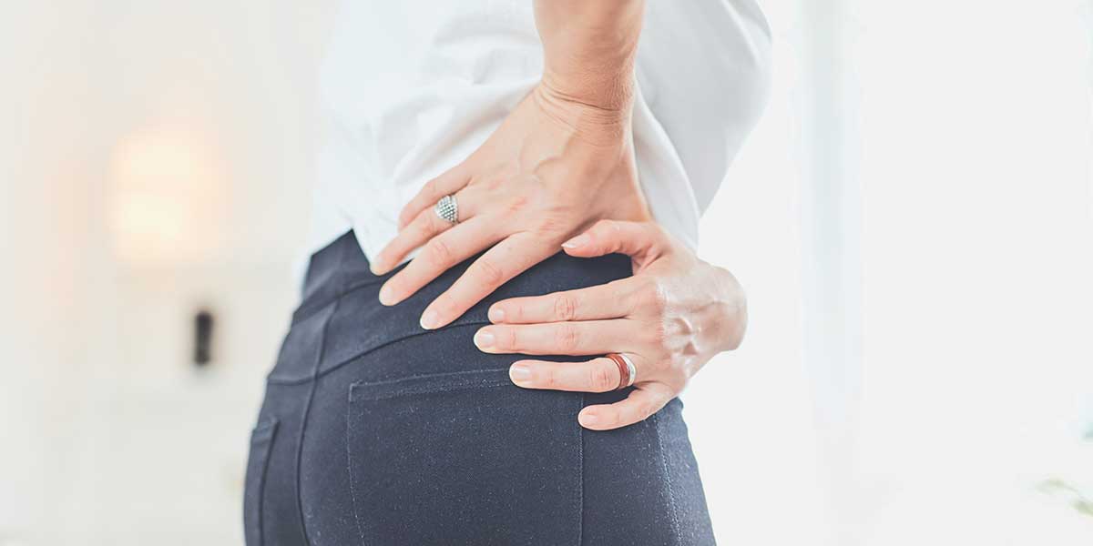 Person holding their lower back and hip in pain, illustrating sciatic nerve discomfort caused by non-herniated disc triggers.