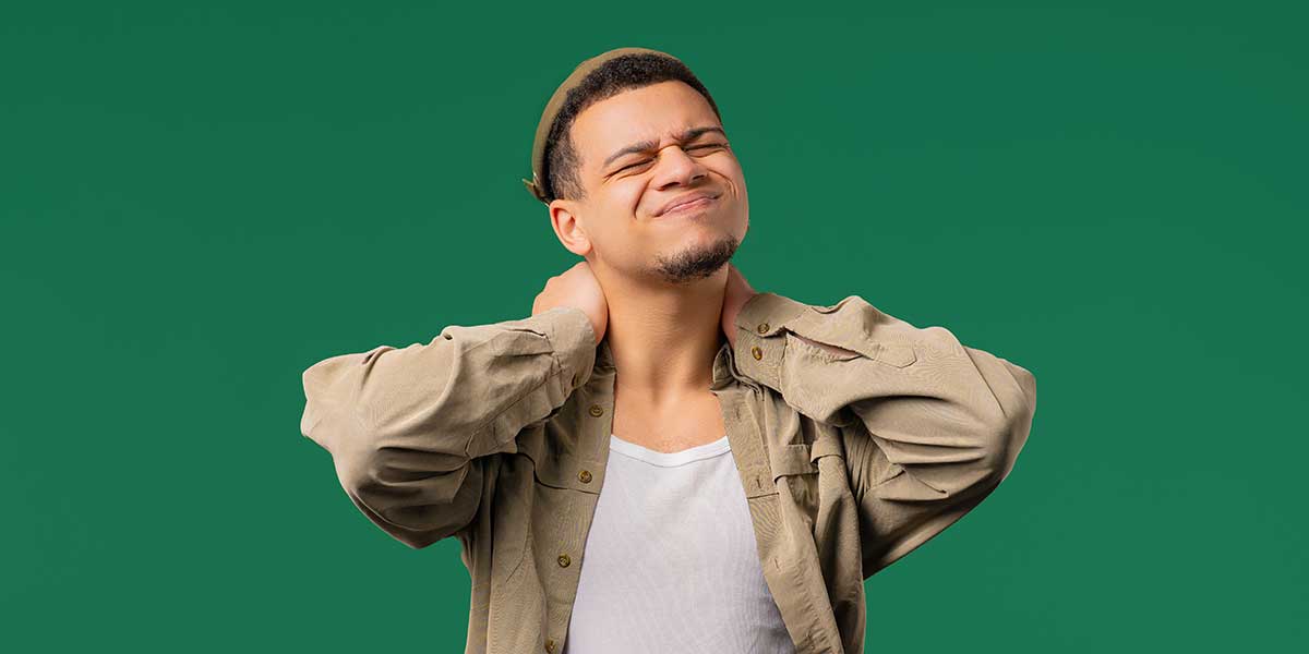Man grimacing while clutching both sides of his neck in pain, depicting muscle stiffness experienced when turning the head.